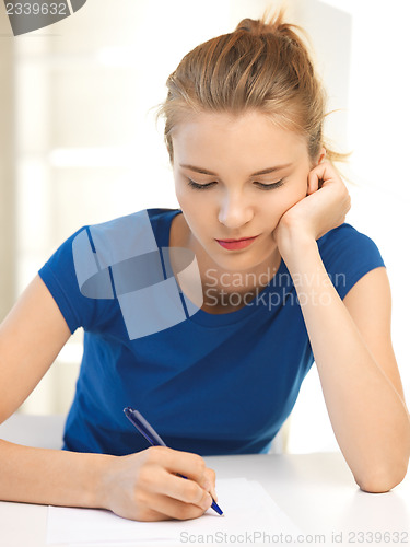 Image of pensive teenage girl with pen and paper
