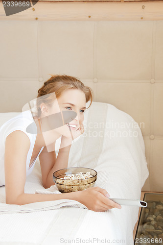 Image of happy teenage girl with TV remote and popcorn