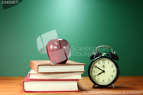 Image of School Books, Apple and Clock on Desk at School