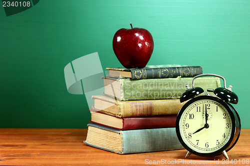 Image of School Books, Apple and Clock on Desk at School