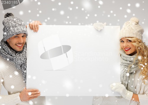 Image of couple in a winter clothes holding blank board