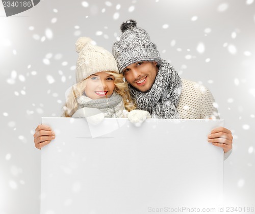 Image of couple in a winter clothes holding blank board