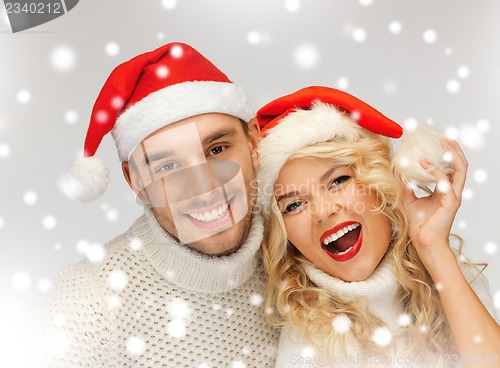 Image of family couple in sweaters and santa's hats