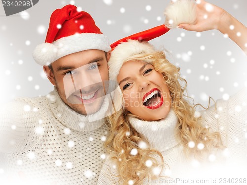 Image of family couple in sweaters and santa's hats