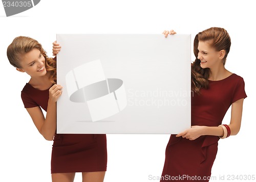 Image of two teenage girls in red dresses with blank board