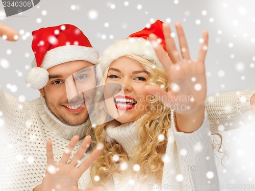 Image of family couple in sweaters and santa's hats