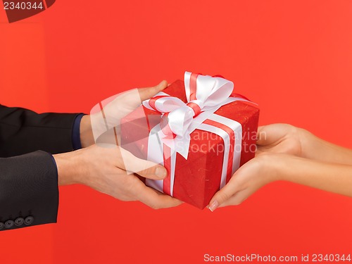 Image of man and woman's hands with gift box