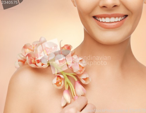 Image of woman's shoulder and hands holding orchid flower