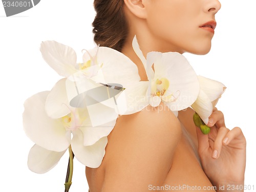 Image of woman's shoulder and hands holding orchid flower