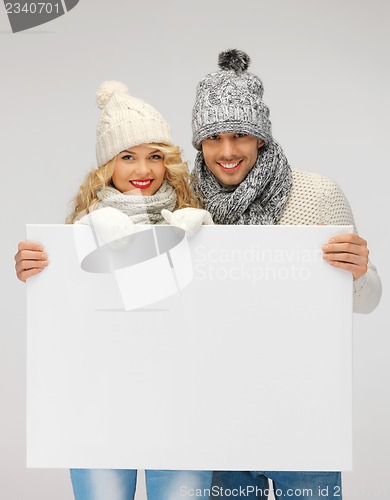 Image of couple in a winter clothes holding blank board