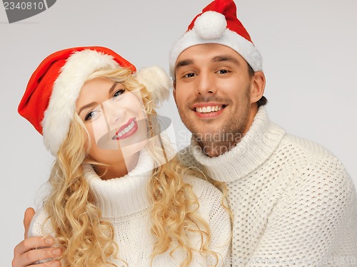 Image of family couple in sweaters and santa's hats