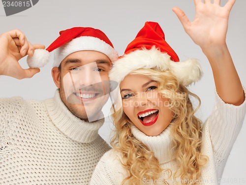 Image of family couple in sweaters and santa's hats