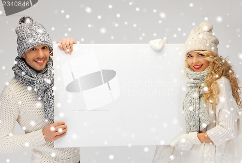 Image of couple in a winter clothes holding blank board