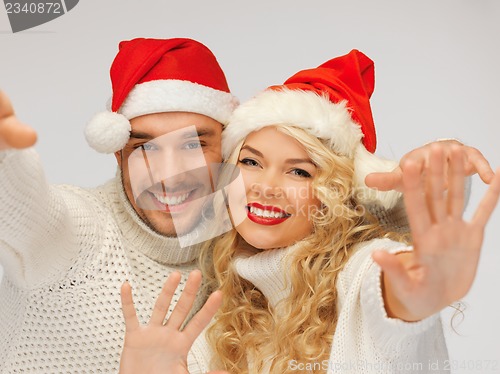 Image of family couple in sweaters and santa's hats