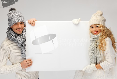 Image of couple in a winter clothes holding blank board