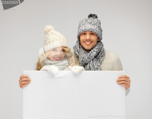 Image of couple in a winter clothes holding blank board