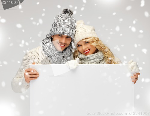 Image of couple in a winter clothes holding blank board