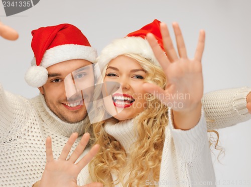 Image of family couple in sweaters and santa's hats