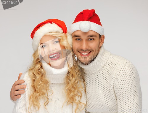 Image of family couple in sweaters and santa's hats