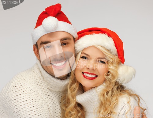 Image of family couple in sweaters and santa's hats