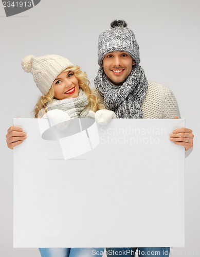 Image of couple in a winter clothes holding blank board