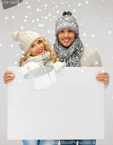 Image of couple in a winter clothes holding blank board