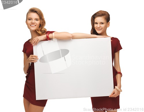 Image of two teenage girls in red dresses with blank board