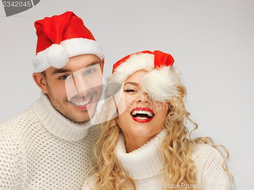 Image of family couple in sweaters and santa's hats