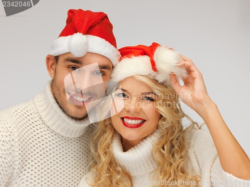 Image of family couple in sweaters and santa's hats