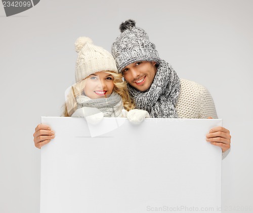 Image of couple in a winter clothes holding blank board