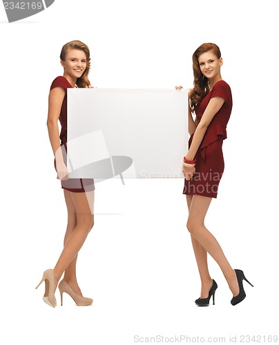 Image of two teenage girls in red dresses with blank board