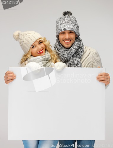 Image of couple in a winter clothes holding blank board