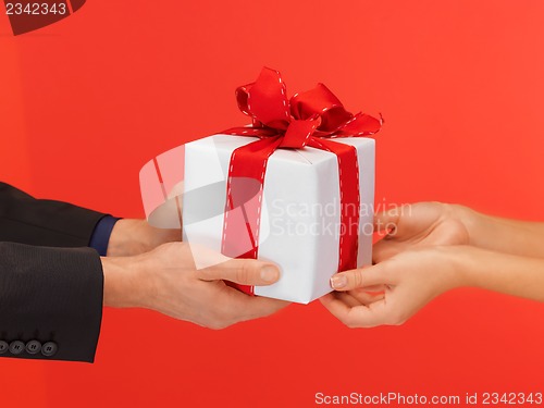 Image of man and woman's hands with gift box