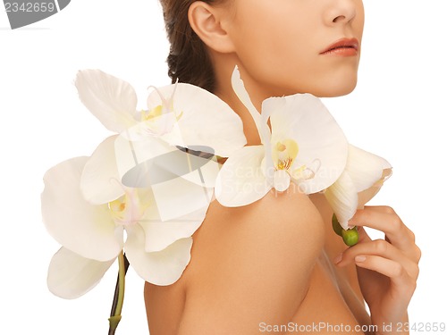 Image of woman's shoulder and hands holding orchid flower