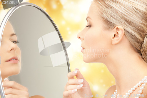 Image of beautiful woman with pearl beads and mirror