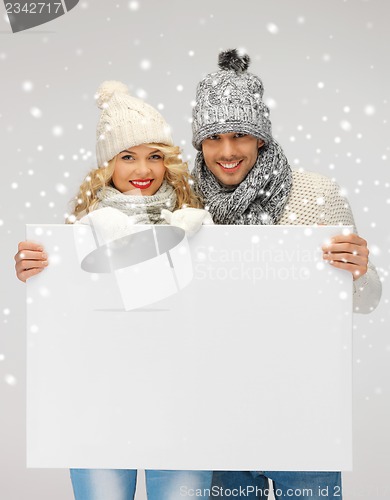 Image of couple in a winter clothes holding blank board