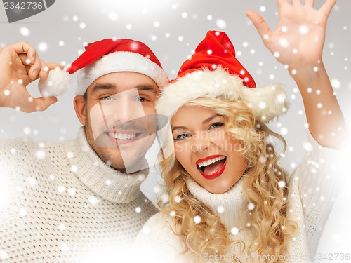 Image of family couple in sweaters and santa's hats