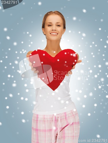 Image of happy and smiling woman with heart-shaped pillow