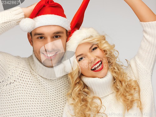 Image of family couple in sweaters and santa's hats