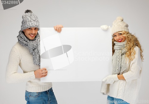 Image of couple in a winter clothes holding blank board
