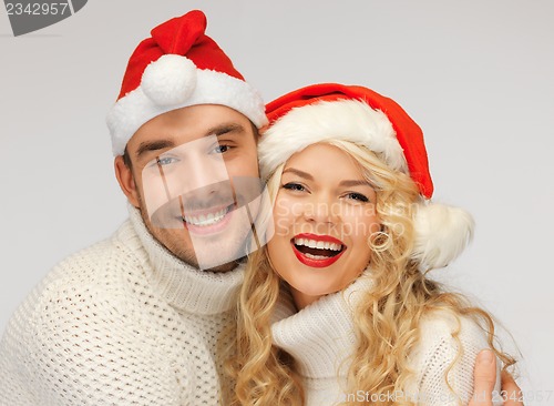 Image of family couple in sweaters and santa's hats