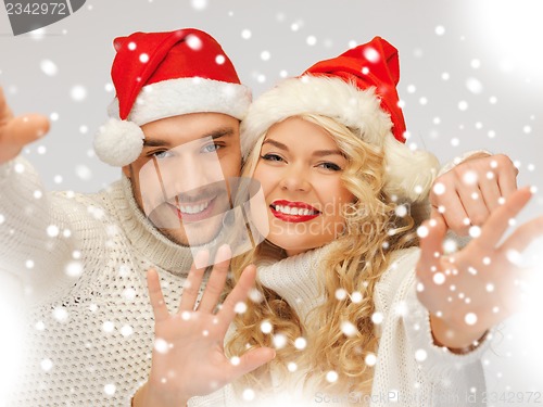 Image of family couple in sweaters and santa's hats