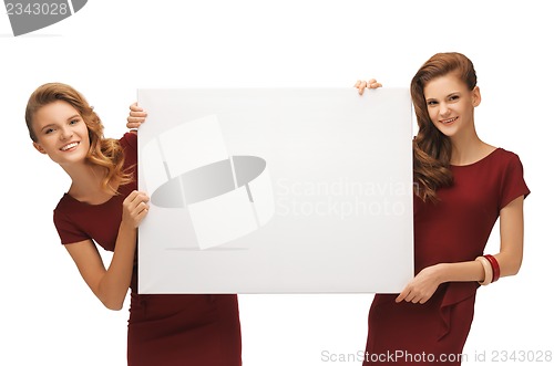 Image of two teenage girls in red dresses with blank board