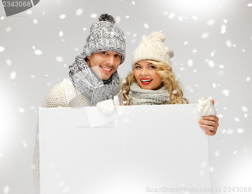 Image of couple in a winter clothes holding blank board