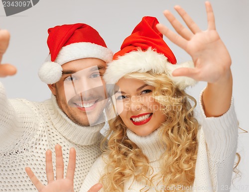 Image of family couple in sweaters and santa's hats