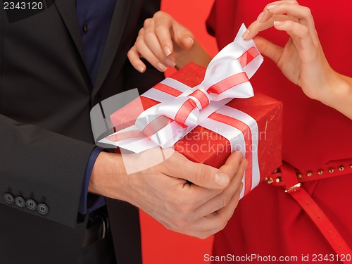 Image of man and woman's hands with gift box