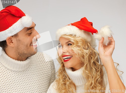 Image of family couple in sweaters and santa's hats