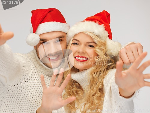 Image of family couple in sweaters and santa's hats