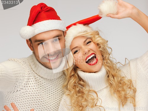 Image of family couple in sweaters and santa's hats