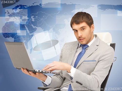 Image of young businessman sitting in chair with laptop
